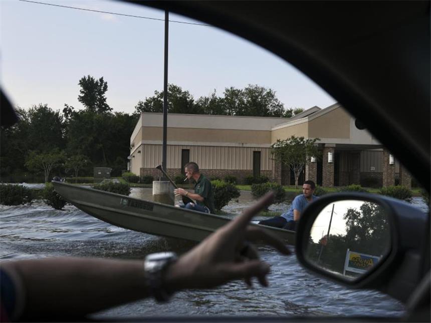 Hochwasser in Texas: Furcht vor Bakterien und Chemikalien Zwei Männer paddeln in Beaumont auf einer überschwemmten Straße in einem Boot. Foto: Carol Guzy