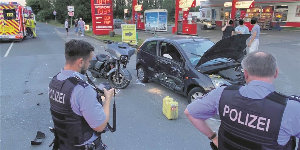 Zwei Polizisten nehmen einen Unfall mit Motorrad und Auto auf.