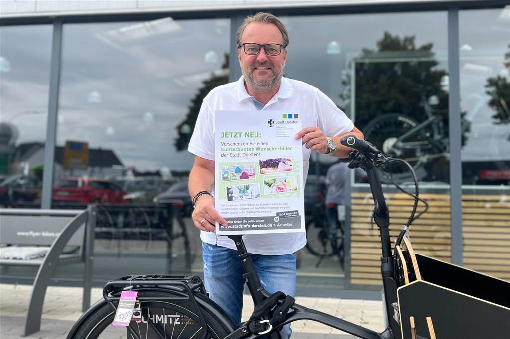Neuer Dorsten-Gutschein: Mehr als 40 Geschäfte machen zum Start mit Klaus Schmitz von Zweirad Schmitz hält ein Werbeplakat für den Wunscherfüller-Gutschein in Händen.